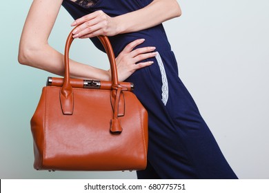 Elegant Outfit. Stylish Woman Fashionable Girl With Brown Leather Handbag Bag On Green. Fashion And Female Beauty.