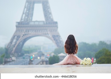 Elegant Parisian woman in pink tutu dress with white roses sitting near the Eiffel tower at Trocadero view point in Paris, France, back view - Powered by Shutterstock