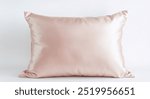 Elegant pink satin pillow with a subtle texture, isolated on white, suitable for luxurious bedroom settings.