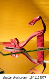 Elegant Pink Snakeskin Heeled Sandals On Mirror Surface On Yellow Background