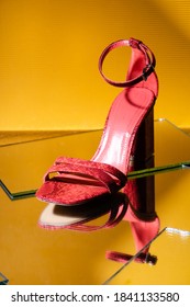 Elegant Pink Snakeskin Heeled Sandals On Mirror Surface On Yellow Background