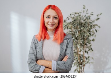 Elegant Pink-haired Woman Stands Against White Wall In Empty Room, Girl Has Arms Crossed Over Chest She Smiles At Camera Real Estate Agent Insurance Adjuster Corporate Office Worker Businesswoman