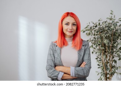 Elegant Pink-haired Woman Stands Against White Wall In Empty Room, Girl Has Arms Crossed Over Chest She Smiles At Camera Real Estate Agent Insurance Adjuster Corporate Office Worker Businesswoman