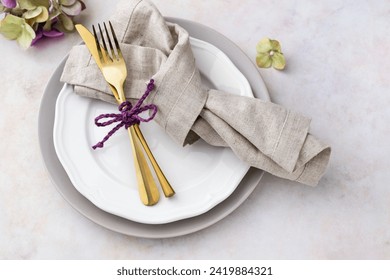 Elegant plate arrangement with folded napkin and golden cutlery on table; simple spring place setting idea - Powered by Shutterstock