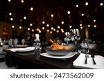 Elegant plated dish in a sophisticated restaurant setting with warm bokeh lighting in the background, highlighting the ambiance and fine dining experience.