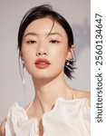 Elegant Portrait of a Woman with Minimal Makeup and Stylish Earrings in Soft Lighting.