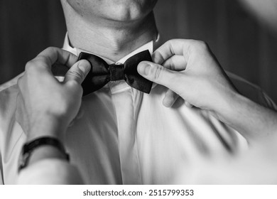 Elegant Preparations: Hands Perfectly Adjusting a Classic Bow Tie in Black and White. - Powered by Shutterstock