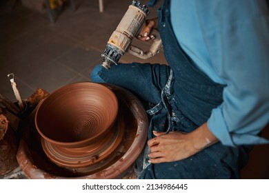 Elegant pretty craft woman holding blowtorch in hand while making clay bowl in pottery workshop - Powered by Shutterstock