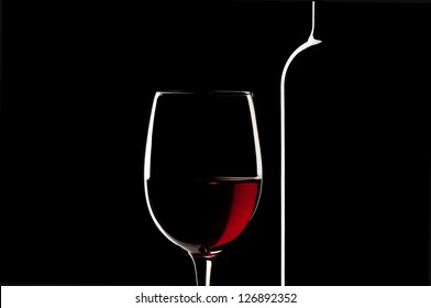 Elegant red wine glass and a wine bottle in black background - Powered by Shutterstock