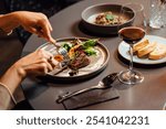 Elegant restaurant dining scene featuring ostrich fillet with grilled vegetables, fresh salad, and red wine, captured in a sophisticated, modern setting.