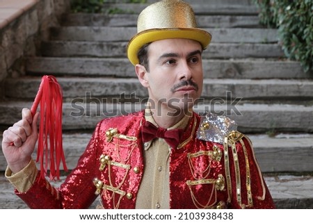 Elegant ringmaster holding red leather whip
