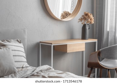 Elegant Round Mirror In Wooden Frame Above Fancy Console Table With Flowers In Vase In Trendy Bedroom Interior With Beige Vase