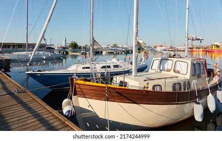 Elegant sailing boat (motorsailer) moored to a pier in a yacht marina. Transportation, pleasure craft, recreation, sport, leisure activity themes