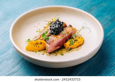 Elegant seared duck breast adorned with caviar and mango puree on a white plate - Powered by Shutterstock