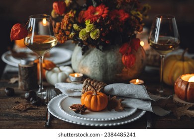 Elegant seasonal fall table setting with floral composition in a pumpkin vase as a centrepiece. White wine, burning candles, romantic cozy atmosphere of family dinner, private autumn wedding - Powered by Shutterstock