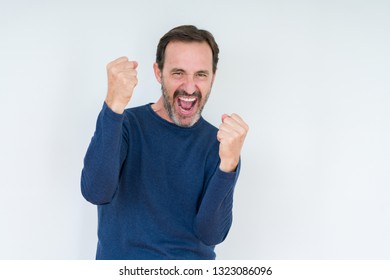 Elegant senior man over isolated background very happy and excited doing winner gesture with arms raised, smiling and screaming for success. Celebration concept. - Shutterstock ID 1323086096