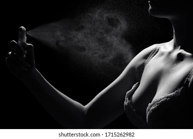 Elegant sensual young woman holding perfume, fashion photo. Women's perfume in hand on a black background.