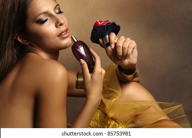elegant sensual young woman holding perfume, golden tones, small amount of grain added