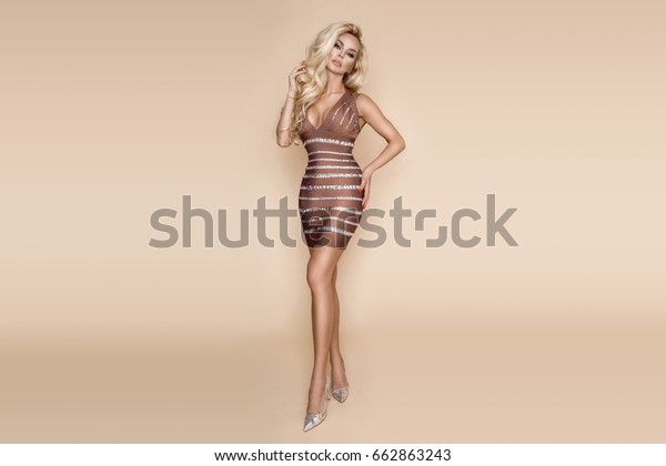 Elegant sexy woman in luxury\
crystals dress. Sensual shapely model in mini dress isolated on\
beige, pastel background. Elegant and luxury woman. Spring\
fashion.