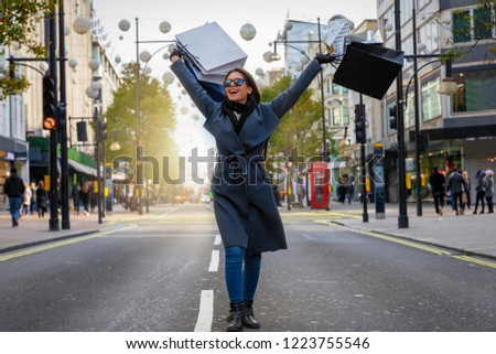 Elegant shopping city woman with many shopping bags in her hand walking down Oxford Street and beeing happy, London