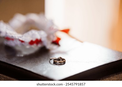 Elegant Silver Wedding Rings Resting on a Dark Wooden Surface with a Blurred Floral Arrangement. - Powered by Shutterstock