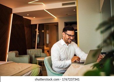 Elegant smiling man using laptop in the luxury hotel room, portrait. - Powered by Shutterstock