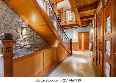 Elegant stairway and entry foyer with stone walls curved staircase carpeted in green hand carved finial and large windows