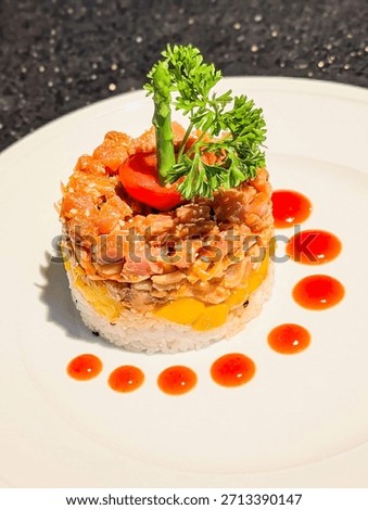 Elegant sushi-style stack featuring layers of white rice, diced mango, and finely chopped salmon with sesame.