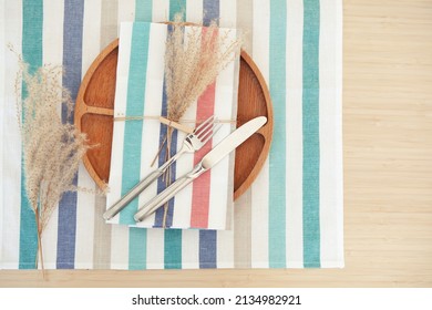 Elegant table place setting, wooden plate with decor on striped napkin and cutlery. Copy space for text - Powered by Shutterstock