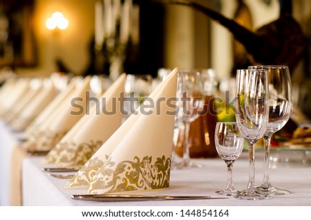Elegant table set for a catered function with a low angle shallow depth of field view of the linen and glassware