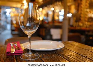 Elegant table setting in a cozy restaurant with empty wine glass, white plate, and silver cutlery on rustic wooden table - Powered by Shutterstock