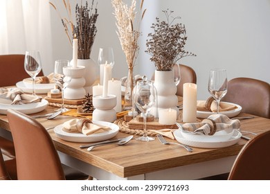 Elegant table setting with dried flowers, burning candles and pine cones - Powered by Shutterstock