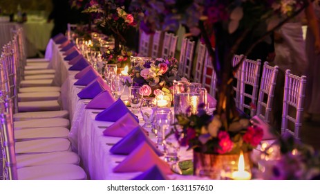 Elegant table setting with plates, glasses, cutlery and floral arrangement, decorated with candle light for special social events.