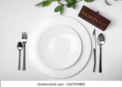 Elegant Table Setting With RESERVED Sign On White Background, Top View