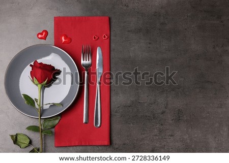 Elegant table setting with rose on grey background, flat lay. Space for text