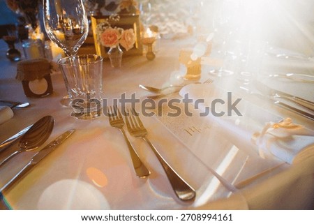Elegant table setting for a wedding reception or special event, featuring silverware, glasses, flowers, and a 'mr.' place card under warm sunlight