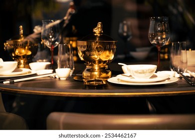 Elegant table setup featuring ornate golden pot, surrounded by fine glassware and crockery, bathed in warm light, creating a luxurious atmosphere. - Powered by Shutterstock