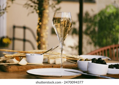 Elegant tall flute of chilled sparkling champagne with different snacks on an elegant formal dining table at outdoor cafe or restaurant in pedestrian street in Europe. Luxury served table at terrace. - Powered by Shutterstock