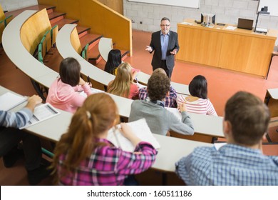 Elegant teacher with students sitting at the college lecture hall