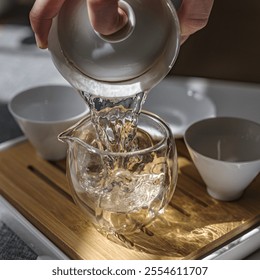 An Elegant Teapot Gracefully Pouring Water into a Clear and Beautiful Glass Pitcher - Powered by Shutterstock