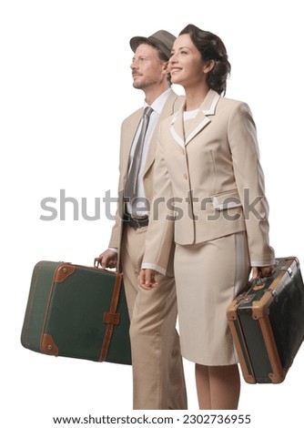 Elegant vintage couple walking and holding suitcases, travel concept