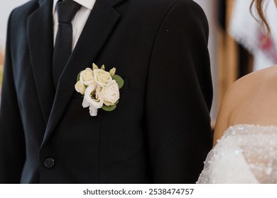 Elegant wedding attire featuring groom's boutonniere and bride's gown details. - Powered by Shutterstock