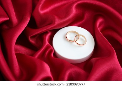 Elegant Wedding Background With Gold Rings On Red Satin Material.