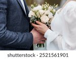 Elegant Wedding Couple Holding a Beautiful Bouquet of White and Green Flowers.