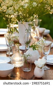 Elegant Wedding Dinner Table Decorated With White Dishes, Flowers In Glass Vases. Festive Atmosphere, Luxury Party. Sunset, Bright Summer Evening. Close Up, Details