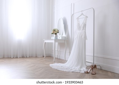 Elegant Wedding Dress Hanging On Rack Indoors