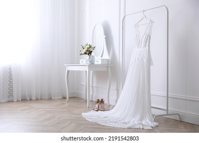 Elegant Wedding Dress Hanging On Rack Indoors