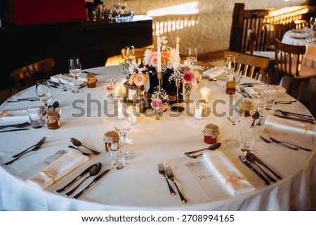 Elegant wedding reception table set with flowers, lit candles, and personalized favors, creating a warm, festive atmosphere