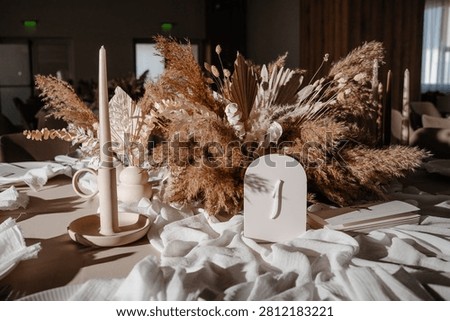 Elegant wedding reception table setting featuring delicate neutral decorations, fine dinnerware, and floral elements for a sophisticated event.