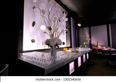 Elegant white, black and silver themed wedding reception drinks table with striking hydrangea and lily floral displays.